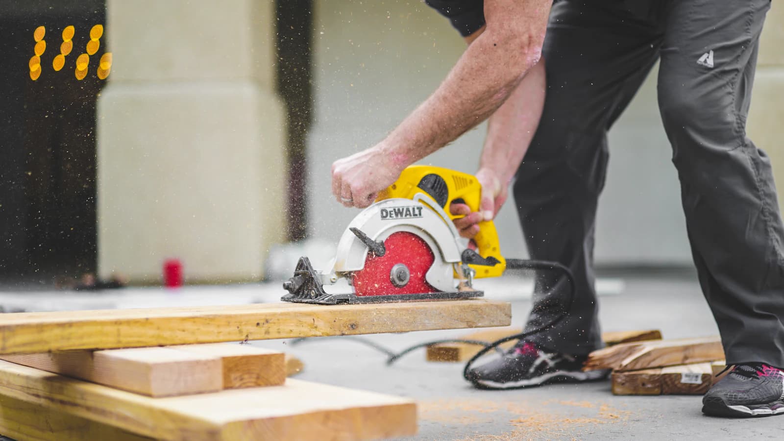 A craftsperson cutting timber, with sawdust catching the light